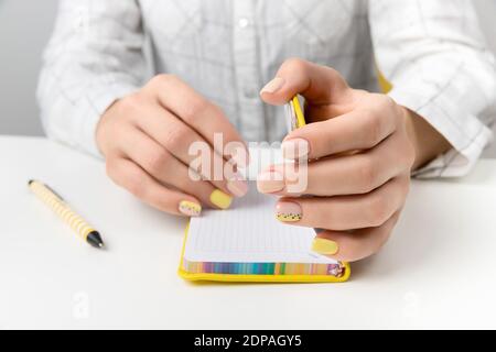 Gepflegte Frauenhände mit Stift und Notizblock. Flat Lay, Draufsicht Arbeit zu Hause Büro Bildungskonzept. Stockfoto