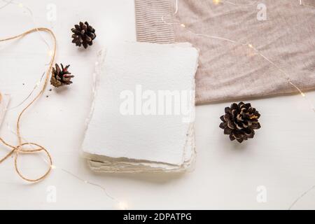 Weihnachtswunsch Konzept. Handgemachtes Papier mit Bastelfaden gebunden. Briefumschlag, Tannenzapfen, Bastelfaden. Hygge-Stil flach Lay, selektiver Fokus Stockfoto