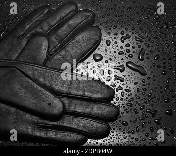 Lederhandschuhe Nahaufnahme auf schwarzem Hintergrund mit Wassertropfen. Modekonzept Stockfoto