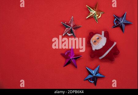 Weihnachtskomposition. Draufsicht Weihnachtsmann umgeben von bunten Sternen auf rotem Hintergrund. Stockfoto