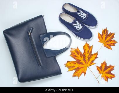 Herbstkollektion. Ledertasche, Stoffschuhe, herbstliche Blätter auf weißem Hintergrund. Saisonale Accessoires. Draufsicht. Stockfoto