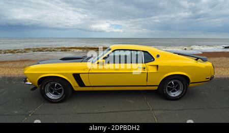 Classic Yellow Ford Mustang auf Strandpromenade Strand und Meer im Hintergrund geparkt. Stockfoto