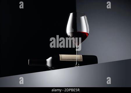 Glas und Flasche Rotwein auf dunklem Hintergrund. Speicherplatz kopieren. Stockfoto
