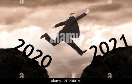 Mann springt von 2020 bis 2021, Neujahr Konzept Stockfoto