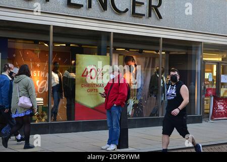 Cambridge, Großbritannien, 19-12-2020. Schaufensterposter Werbung Verkauf auf Geschenke im Kaufhaus, Erwachsene vorbei mit Gesichtsbedeckungen gehen. Stockfoto