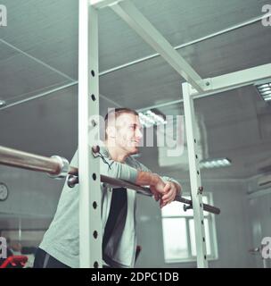 Schöner männlicher Athlet ruht sich vom Training im Fitnessstudio aus Und lächelnd und geradlinig Stockfoto