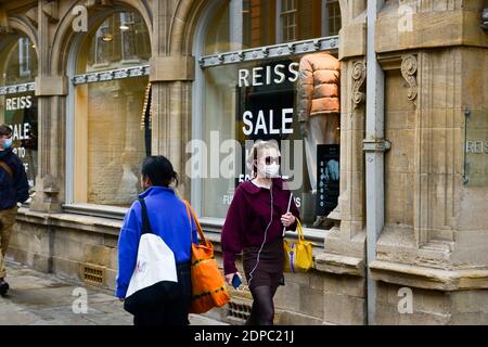 Cambridge, Großbritannien, 19-12-2020. Erwachsener mit Gesichtsmaske geht an einem Einzelhandelsgeschäft vorbei, in dem das Verkaufsschild im Fenster steht Stockfoto