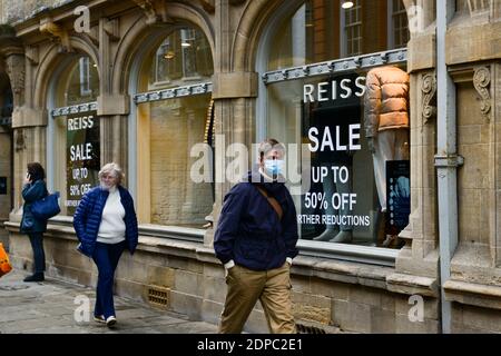 Cambridge, Großbritannien, 19-12-2020. Erwachsener mit Gesichtsmaske geht an einem Einzelhandelsgeschäft vorbei, in dem das Verkaufsschild im Fenster steht Stockfoto