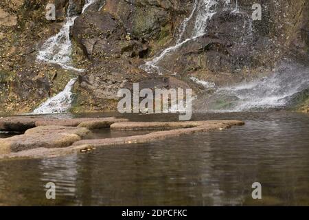 Wasserfall, Wasser fließt den felsigen Felsen hinunter in den See Stockfoto