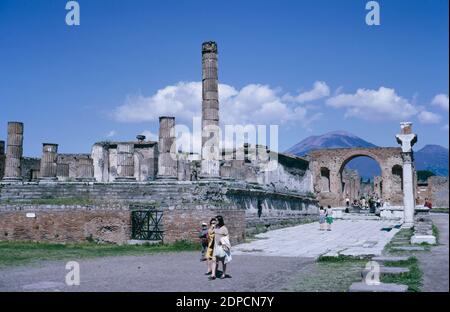 Archiv Scan der Ruinen von Pompeji comune zerstört durch den Ausbruch des Vesuv in AD 79. Jupitertempel mit Triumphbogen, der dem Germanicus gewidmet ist, im Hintergrund der Vesuv. Mai 1968. Stockfoto