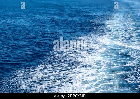 Boot weiße Wake, auf blauem Meeresgrund, Blick vom Schiff. Mittelmeerkreuzfahrt, griechische Inseln Sommerferienkonzept Stockfoto