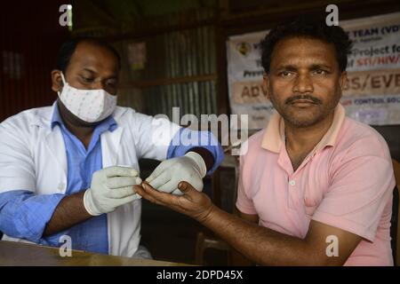 Gesundheitshelfer testen das Blut von Fahrern aus verschiedenen Nutzfahrzeugen an einem Bussstand während eines Beratungs- und HIV-Testcamps, das von der staatlichen AIDS-Kontrollgesellschaft Tripura organisiert wird. Agartala, Tripura, Indien. Stockfoto