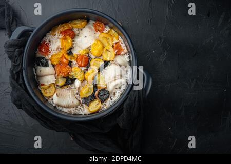 Eine Pfanne fabelhafter Fisch, mit Basmati-Reis und Kirschtomaten, auf schwarzem Hintergrund, Draufsicht mit Platz für Text Stockfoto