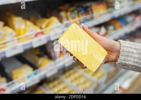 Weibliche Hand hält Käse im Supermarkt Stockfoto