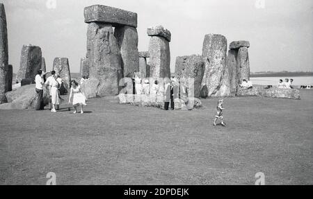 1950er Jahre, historisch, Menschen in Stonehenge, dem berühmten prähistorischen Denkmal in Wiltshire, England, Großbritannien. Zu dieser Zeit, in einer entspannteren Zeit, gingen die Besucher frei zwischen den alten Sarsensteinen und saßen ohne Probleme darauf, was später, wenn der Zutritt zu den Steinen kontrolliert wurde, nicht erlaubt war. Stockfoto