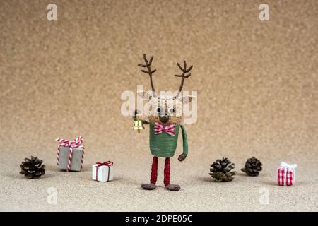 Handgemachte Weihnachten Hirsch Kork Figur mit goldenen Glocke neben Tannenzapfen und Pappschachteln auf Korkholzstruktur in skandinavisch Stilvolles Outfit Stockfoto