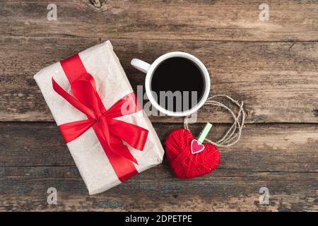 Geschenkbox, Kaffeetasse und Herz auf Holzhintergrund. Stockfoto