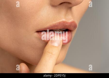 Nahaufnahme der Frau Anwendung feuchtigkeitsspendenden pflegenden Balsam auf ihre Lippen mit dem Finger, um Trockenheit und Schnupfen in der kalten Jahreszeit zu verhindern. Lippenschutz. Stockfoto