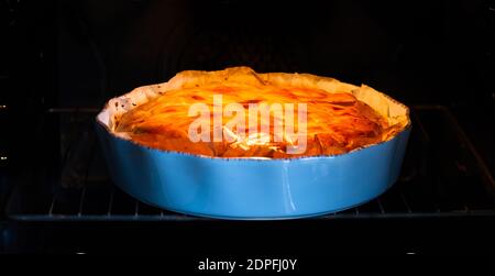 Gebackene Kartoffelpastete im Ofen, in blauer Keramik-Tortenpfanne Stockfoto