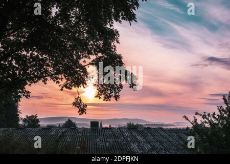 Ein lila oranger Sonnenaufgang mit dunklen Wolken am Morgen Stockfoto