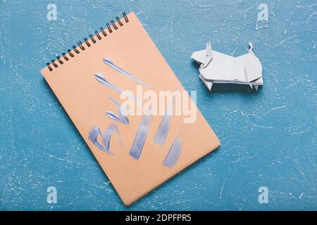 Origami-Stier als Symbol des Jahres 2021 und Notizbuch auf Farbiger Hintergrund Stockfoto