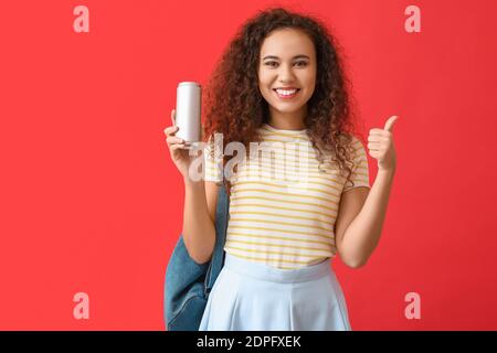 Schöne afroamerikanische Frau mit Soda zeigt Daumen-up auf Farbhintergrund Stockfoto