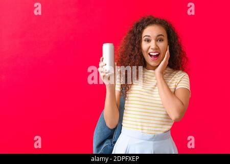 Überrascht afroamerikanische Frau mit Soda auf farbigem Hintergrund Stockfoto
