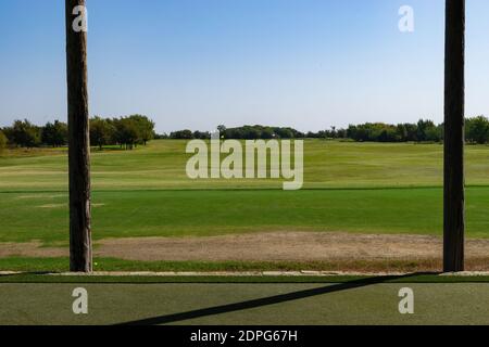 Blick auf eine Golf Driving Range T-Box auf dem ordentlich gemähten Fairway mit verschiedenen farbigen Markern auf bestimmten Entfernungen. Stockfoto