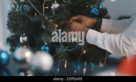 Nahaufnahme, weihnachtsbaumdokoration. afroamerikanischer schwarzer Mann, der den weihnachtsbaum schmückt. Hochwertige Fotos Stockfoto