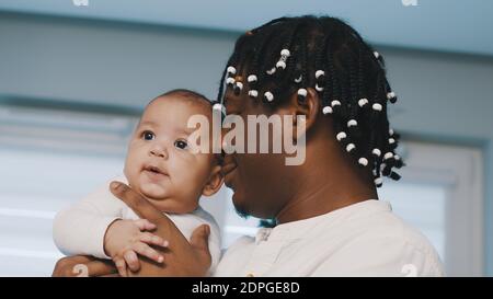 Weihnachtszeit in multirassischer Familie. afroamerikanischer schwarzer Vater hält sein Mulatto-Baby. Hochwertige Fotos Stockfoto