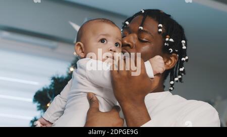 Weihnachtszeit in multirassischer Familie. afroamerikanischer schwarzer Vater hält sein Mulatto-Baby in der Nähe des weihnachtsbaums. Hochwertige Fotos Stockfoto