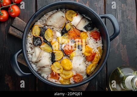 Eine Pfanne fabelhaften Fisch, mit Basmati-Reis und Kirschtomaten, auf alten Holztisch, Blick von oben Stockfoto