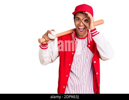 Junger afrikanischer amerikanischer Mann spielt Baseball mit Schläger und Ball Lächelnd glücklich dabei ok Zeichen mit Hand auf Auge schauen Durch die Finger Stockfoto