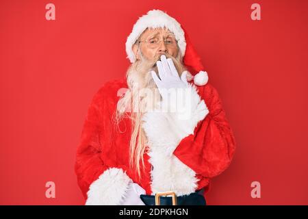 Alter älterer Mann mit grauen Haaren und langem Bart trägt traditionelle weihnachtsmann Kostüm gelangweilt gähnend müde Abdeckung Mund mit der Hand. Rastlos und schläfrig Stockfoto