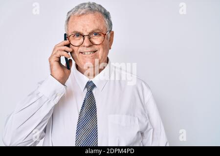 Älterer grauhaariger Mann in Geschäftskleidung, der Gespräche geführt hat Das Smartphone sieht positiv und glücklich stehen und lächeln mit A c Stockfoto