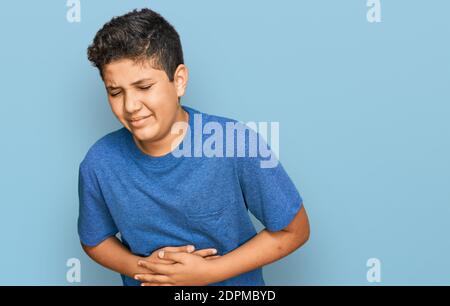 Teenager hispanic Junge trägt Freizeitkleidung mit der Hand auf dem Bauch, weil Verdauungsstörungen, schmerzhafte Krankheit Gefühl unwohl. Schmerzen Konzept. Stockfoto