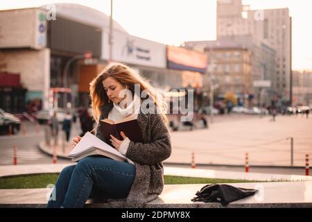 Ernst Teenager Student Mädchen studieren, während in der Stadt sitzen Herbst Stockfoto