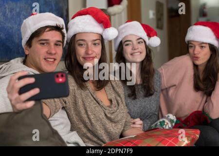 Vier Geschwister im College-Alter tragen Weihnachtsmützen und machen Selfie Stockfoto