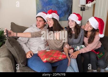 Vier Geschwister im College-Alter tragen Weihnachtsmützen und machen Selfie Stockfoto