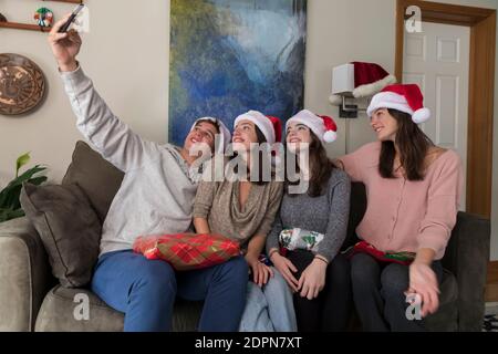 Vier Geschwister im College-Alter tragen Santa Hüte posieren für Selfies Stockfoto