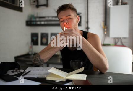 Junger Mann zünden Cannabis Joint, während sie am Tisch sitzen und Arbeit am Lied zu Hause Stockfoto