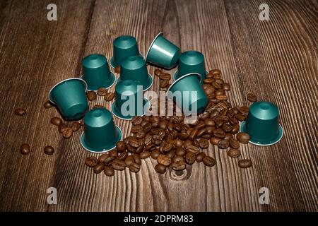 Espresso Kaffeekapseln oder Kaffeepads auf Holzhintergrund mit gerösteten Kaffeebohnen. Nahaufnahme Stockfoto