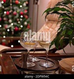 Gin und Tonic mit Zitrone und Gewürzen im Kristallglas Auf dem Tisch neben dem Weihnachtsbaum Stockfoto