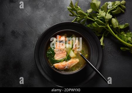 Frische Fischsuppe auf schwarzem Hintergrund. Lachssuppe Stockfoto