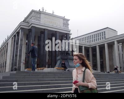 Eine Frau, die eine Gesichtsmaske trägt, geht an einem Denkmal des Schriftstellers Dostojewski im Zentrum Moskaus vorbei. Stockfoto