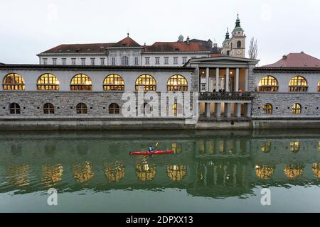 Kayaker in se Kajak Kajakfahren auf Ljubljanica Fluss mit Plecnik Central Market im Hintergrund im Winter, Ljubljana, Slowenien Stockfoto