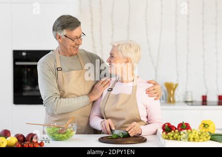 Happy Senior Ehegatten Kochen Salatmachen Stehen In Der Küche Im Haus Stockfoto