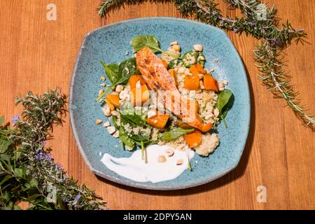 Typischer Fisch frischer Teller, leckerer gegrillter Lachs mit gegrillten Kürbissen und Joghurtsauce auf einem schicken Holztisch. Mediterrane Gerichte mit einem Stockfoto
