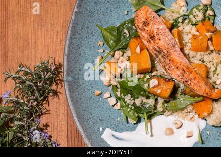 Typischer Fisch frischer Teller, leckerer gegrillter Lachs mit gegrillten Kürbissen und Joghurtsauce auf einem schicken Holztisch. Mediterrane Gerichte mit einem Stockfoto
