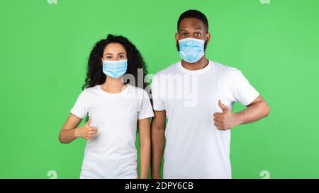 Diverse Paar Trägt Gesichtsmasken Gestikulieren Wie, Grüner Hintergrund, Panorama Stockfoto
